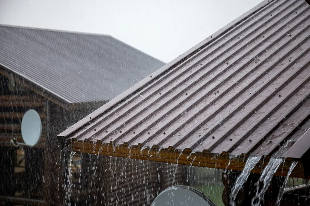 a metal roof with rain expelling off the top