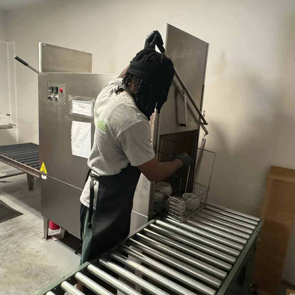 A workers rinsing dishes