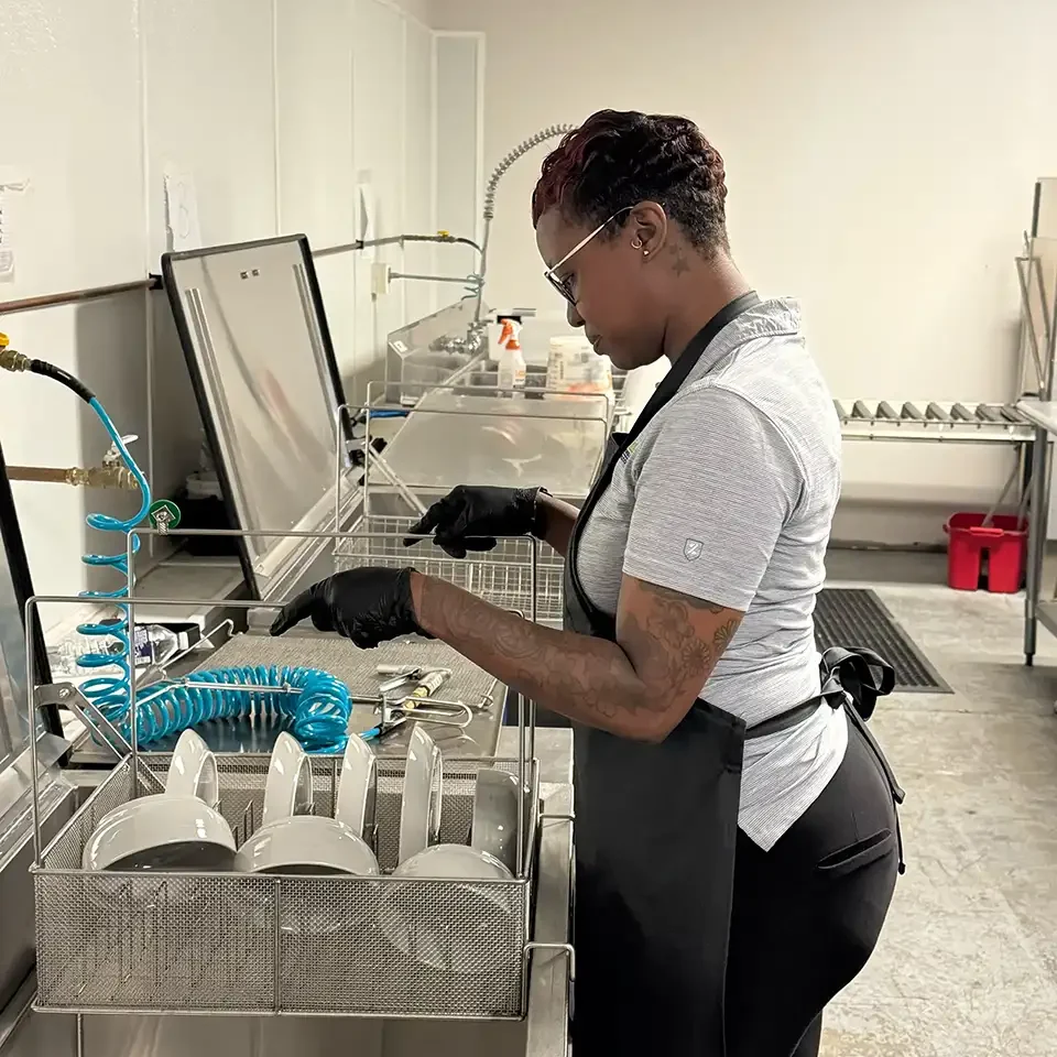 A workers cleaning plates and bowls